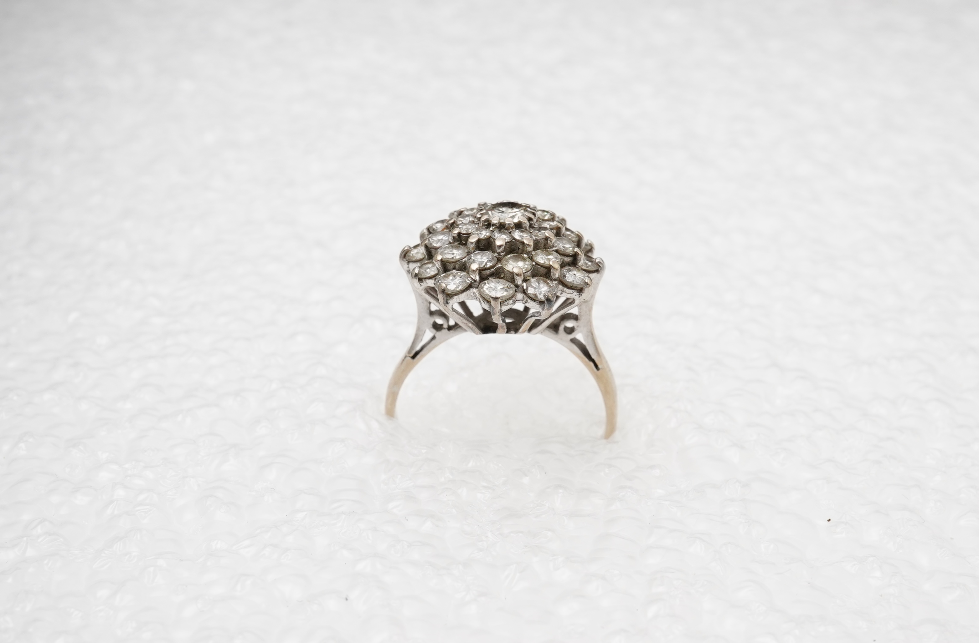 A white gold and diamond cluster ring, set with a concentric arrangement of brilliant-cut diamonds totalling approximately 1.50 carats, size M, gross weight approximately 5 grams